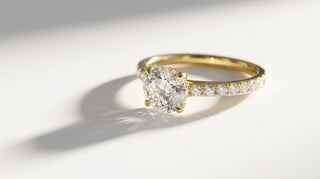Bague de fiançailles Origine Paris en or jaune 18 carats, diamant de synthèse rond sur anneau pavé de diamants, sur fond blanc
