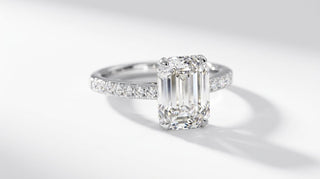 Bague de fiançailles Origine Paris en or blanc 18 carats, diamant de synthèse taille émeraude sur anneau pavé, sur fond blanc