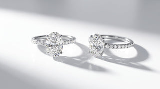 Deux bagues de fiançailles Origine Paris en or blanc 18 carats, diamant de synthèse ovale sur anneau pavé, côte à côte sur fond blanc